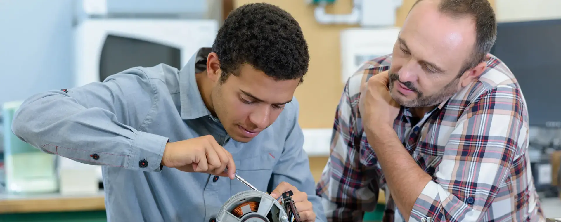 Jongeman repareert een object docent kijkt toe