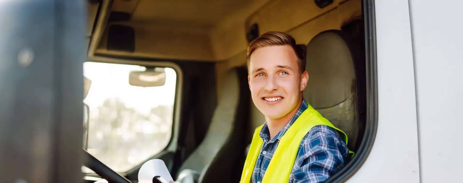 Vrachtwagenchauffeur in geel hesje in cabine vrachtwagen