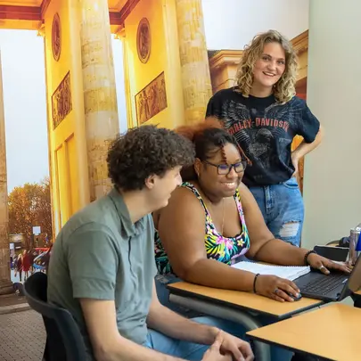 Groepje studenten rond een computer in klaslokaal