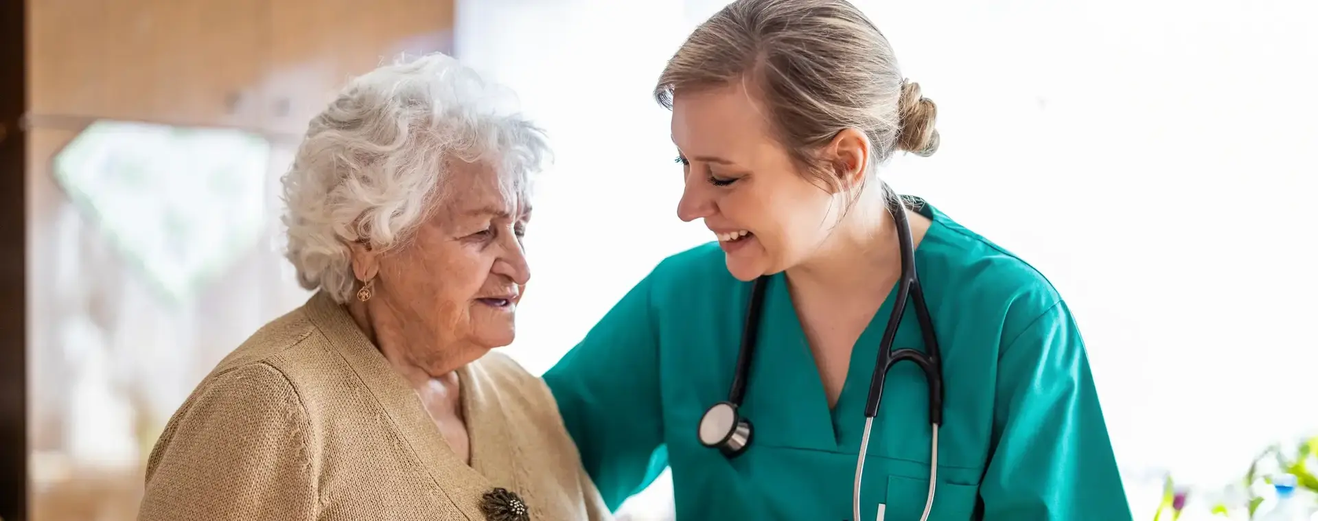 Verzorger ondersteunt oude dame.