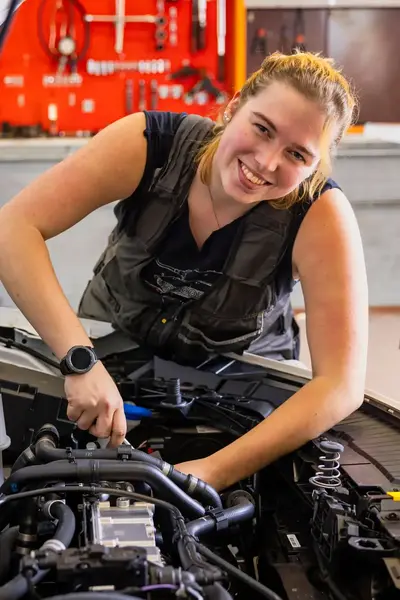 Student sleutelt aan auto in werkplaats. 