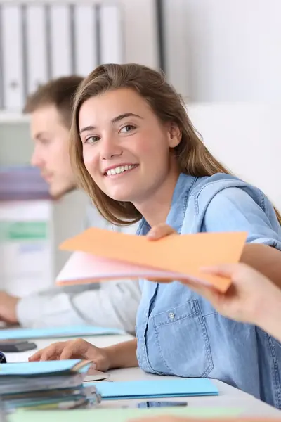 Lachende studente te midden van andere studenten kijkt glimlachend in de camera.