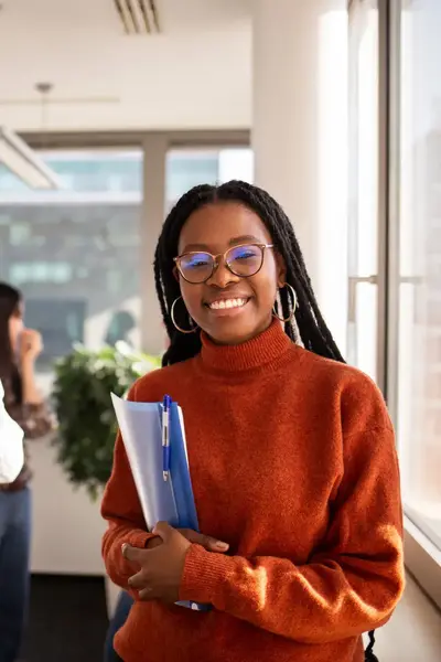 Studente met schriften in de hand met op de achtergrond andere studenten.