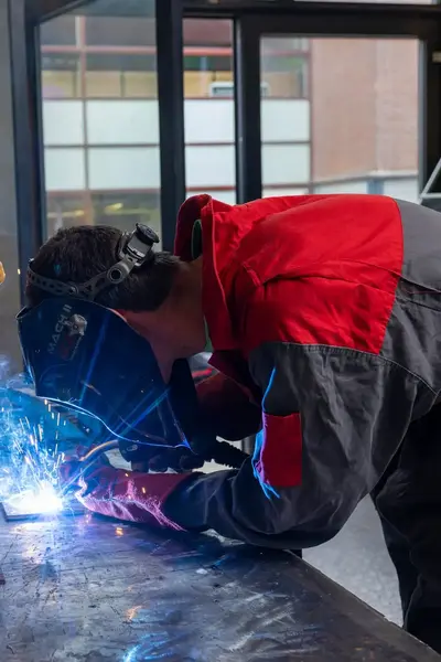 Student lasser met gezichtsbescherming last metalen object