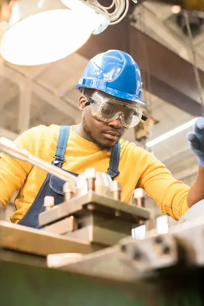 Student met veiligheidsbril en helm inspecteert machine