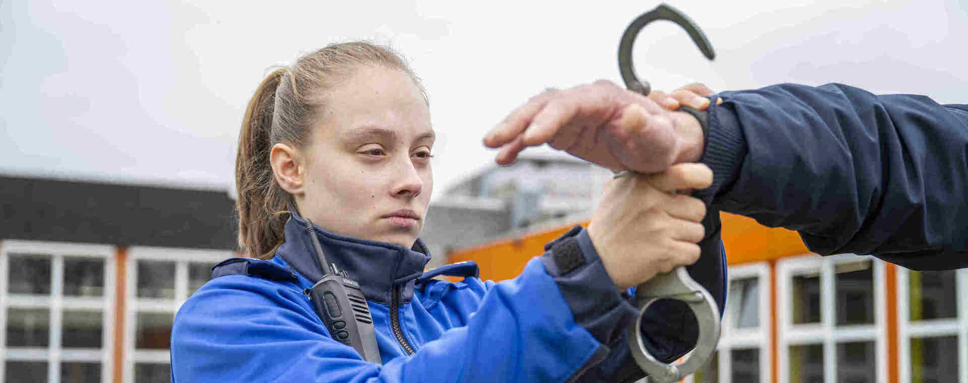 Studente in uniform slaat arrestant in boeien.
