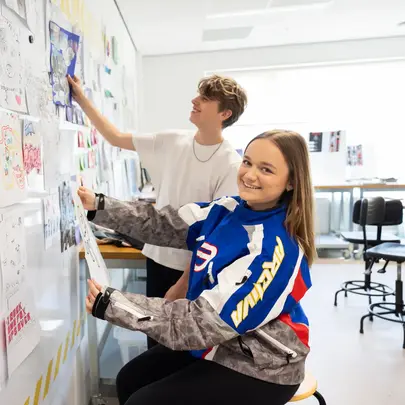 Studenten Media en Vormgeving hangen hun creaties aan de muur. 