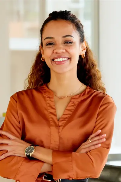 Glimlachtende jongedame op kantoor staand naast een plant