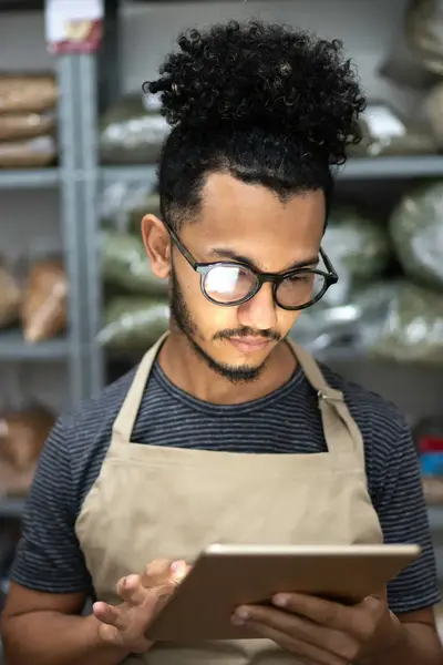 Student met schort om checkt tablet in kruidenierswinkel