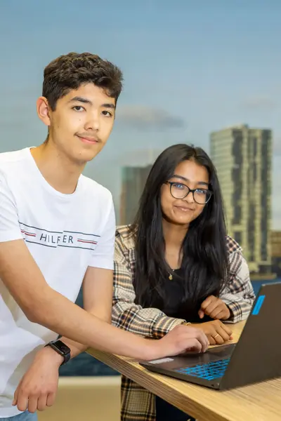 Twee studenten leunen tegen statafel met laptop