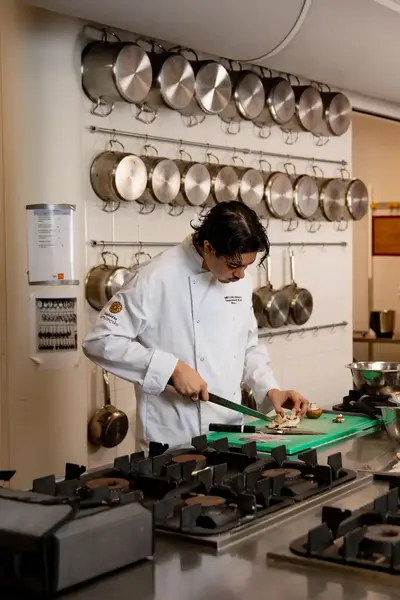 Kokstudent snijdt champignon in leskeuken