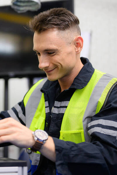 Man in veiligheidshesje sleutelt aan elektrisch apparaat