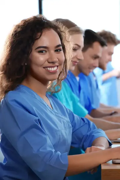 Studenten verpleegkunde in uniform achter laptop
