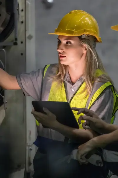 Reparateurs met gele helmen en hesjes inspecteren een machine