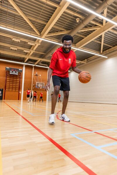 Student MBO College Poort dribbelt met basketbal in gymzaal