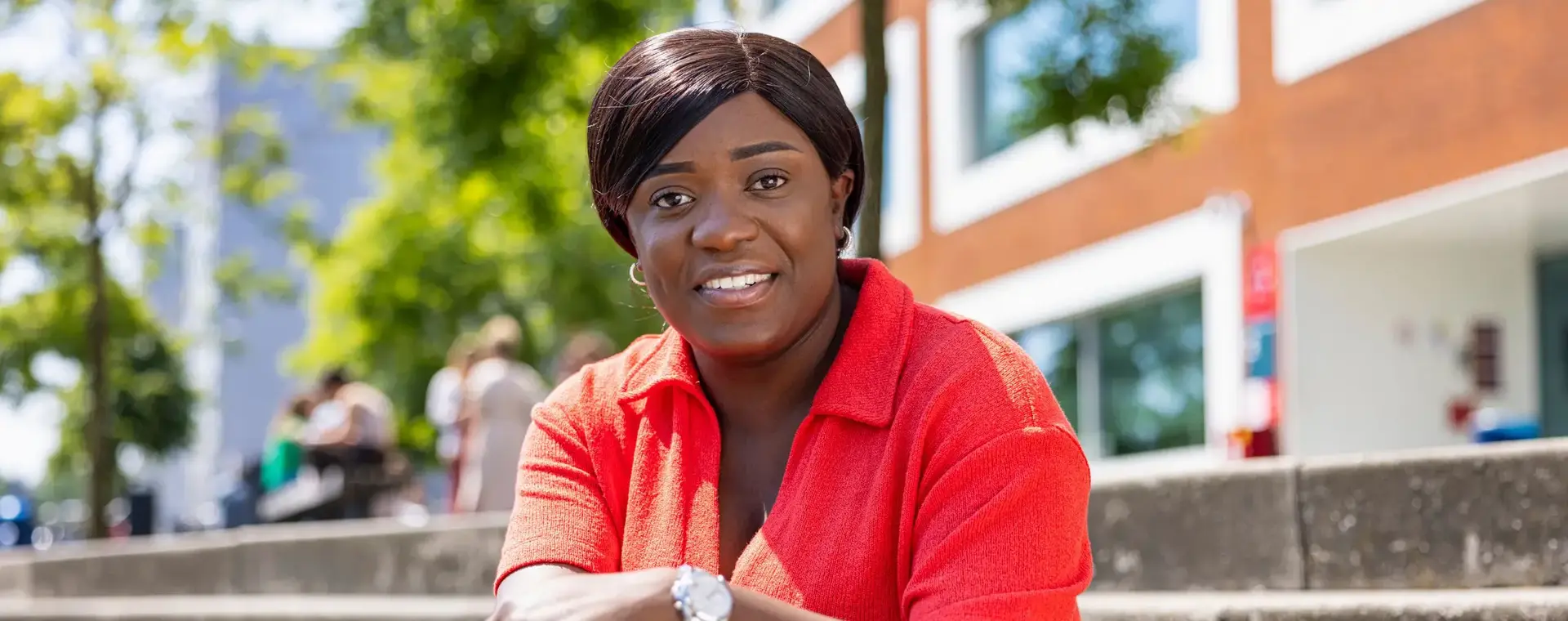 Vrouw met rode blouse zit buiten op stenen trap 