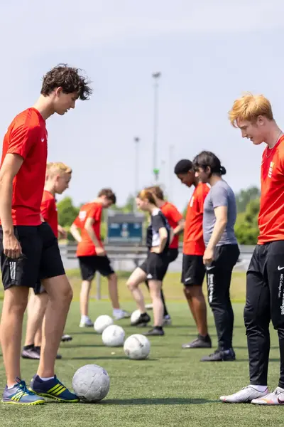 Voetballers staan in een rij tegenover elkaar met een bal in hun midden.