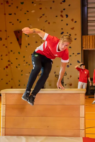 Jongen springt over de bok heen in een sporthal.