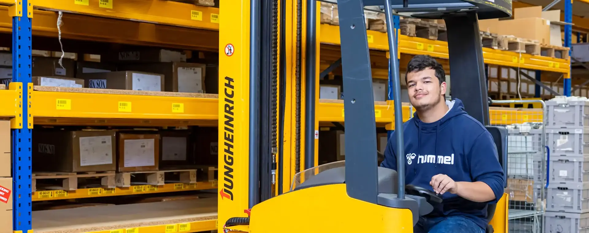 Logistiek medewerker bedient een gele reachtruck in een magazijn.
