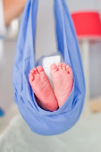 Kraamverzorgende houdt baby omhoog in doek