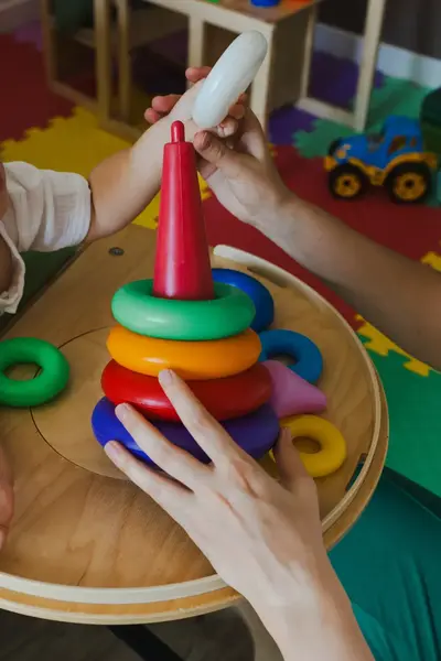 Baby speelt met speelgoed met begeleider