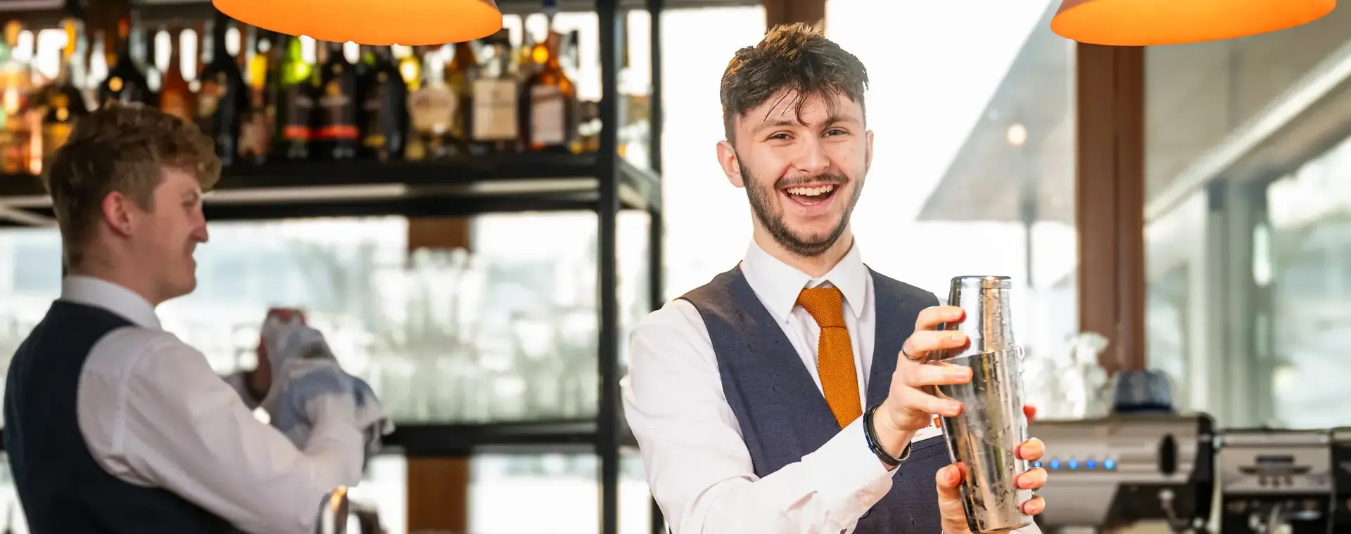 Horecastudent maakt een cocktail achter de bar van een horecazaak