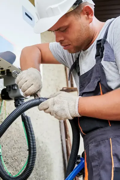 Reparateur herstelt slang aan apparaat buitenmuur