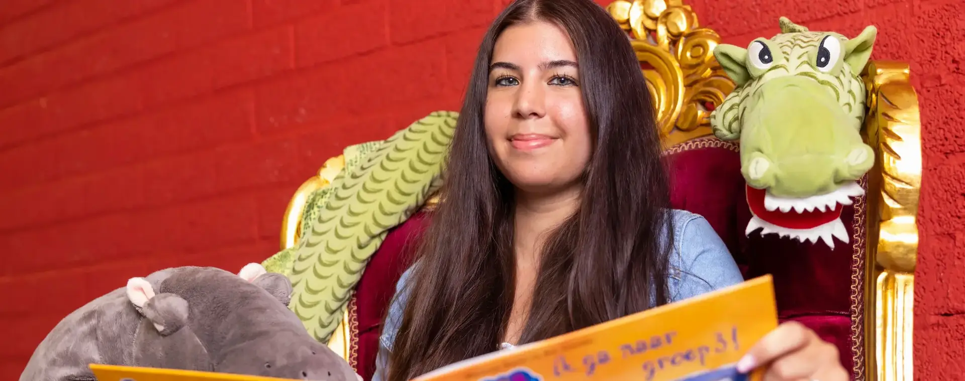 Jonge dame met boek en knuffels in voorleesstoel 