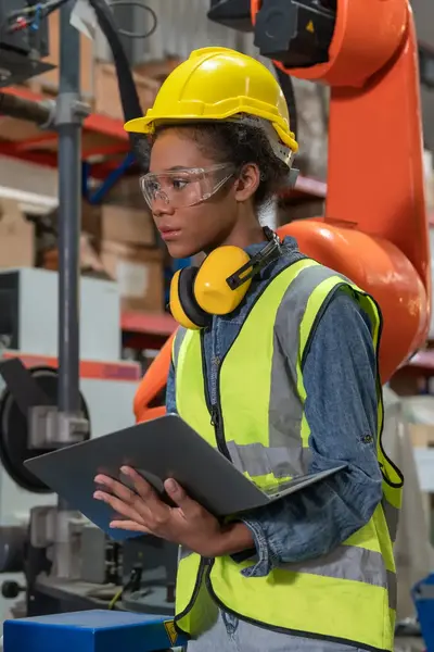 Student met laptop, veiligheidsbril en helm in fabriek