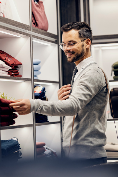 Verkoper in winkel naast wandkast met mooie kleding