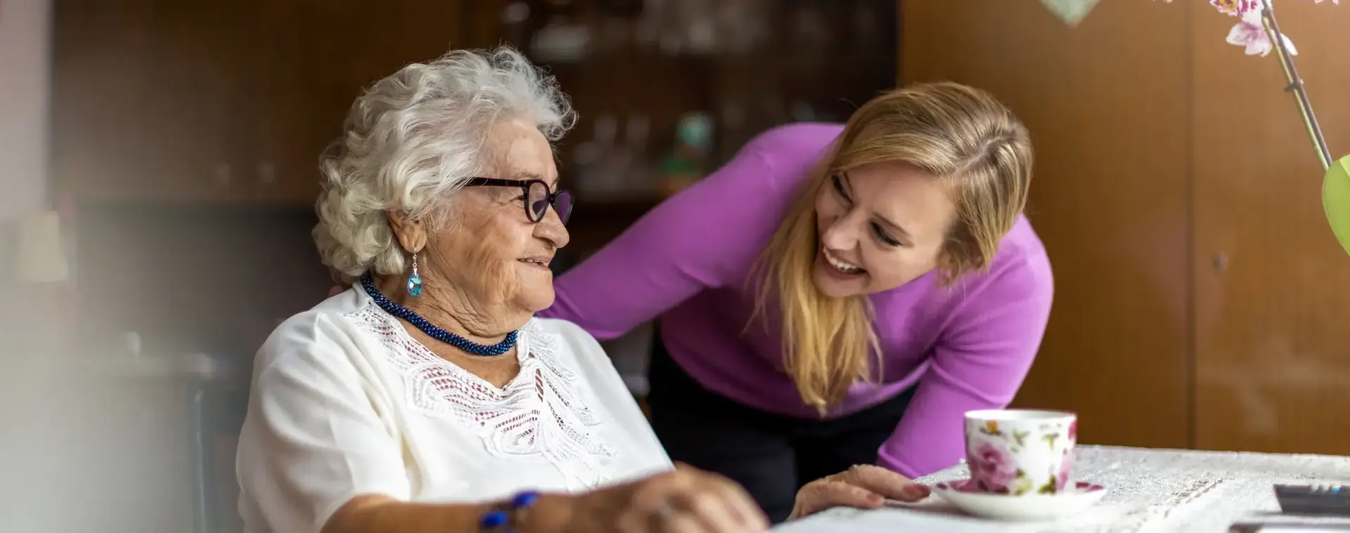 Jonge dame houdt oude dame gezelschap.