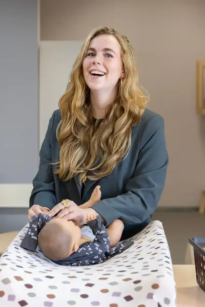 Pedagogisch medewerker verzorgt baby in kinderopvang.