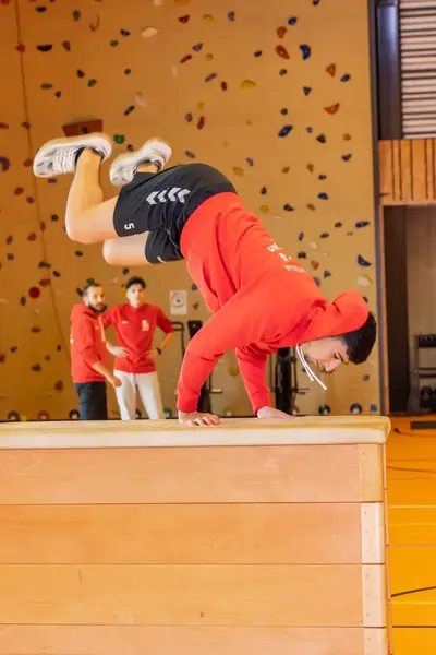 Student in gymzaal springt over een bok heen met z'n handen op de bok.