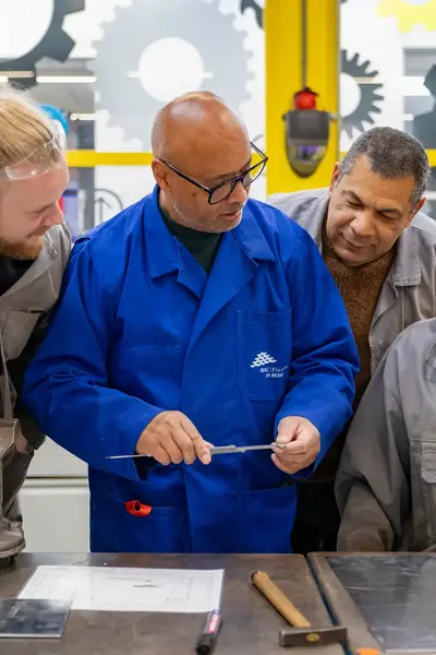 Docent omringd door deelnemers legt de lesstof uit